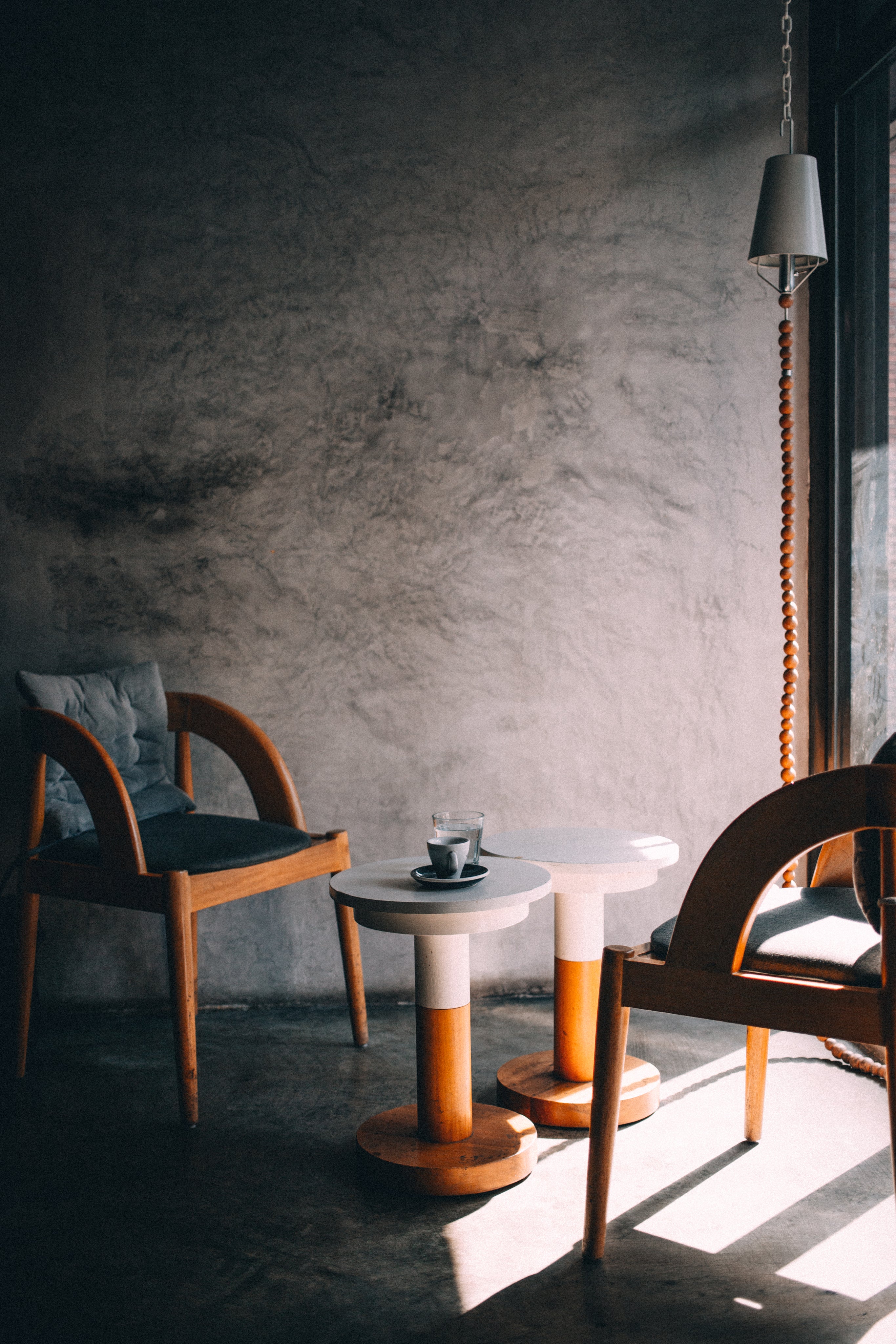 Two empty wooden chairs on either side of a small round table with a coffee cup on it