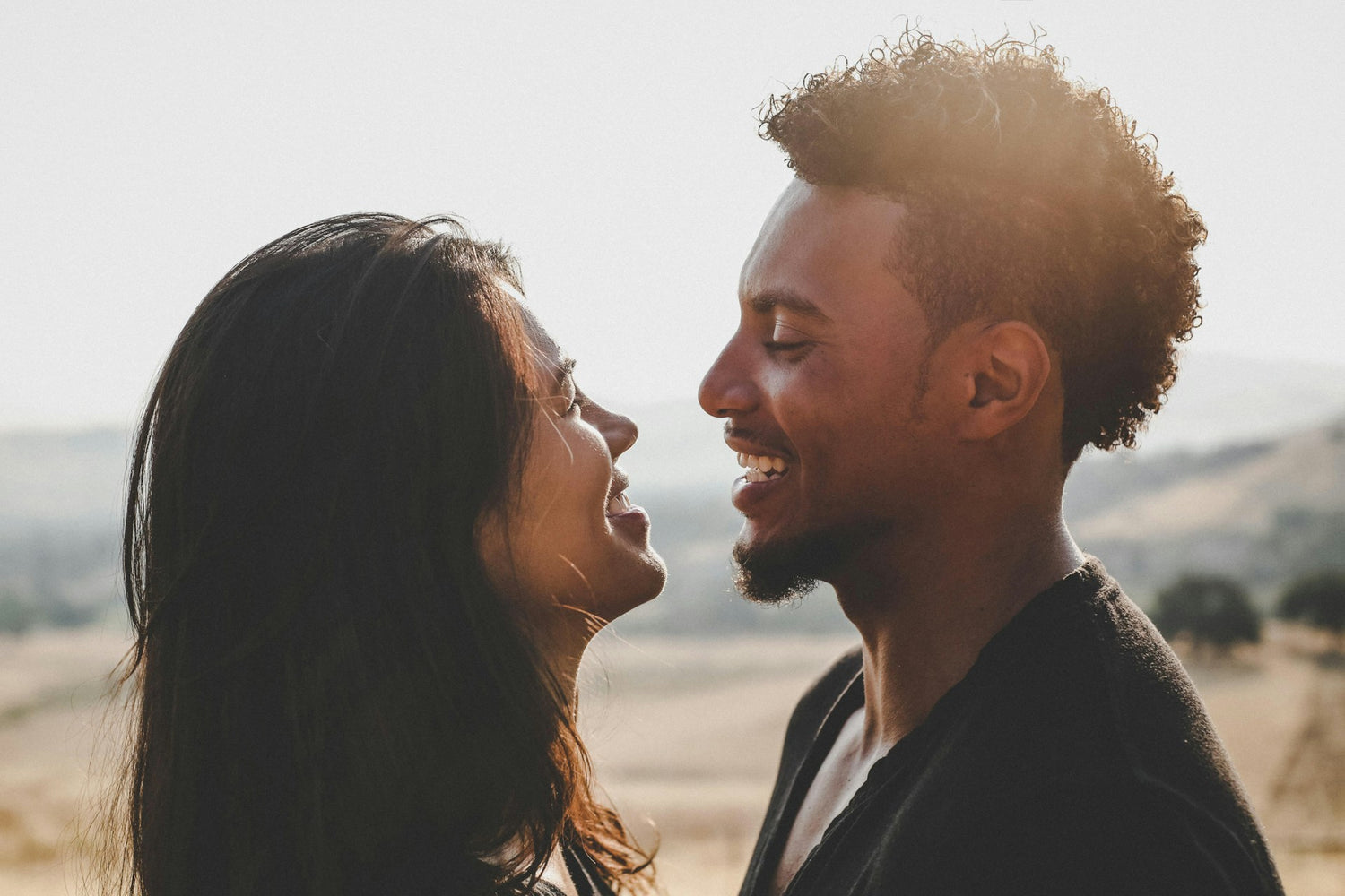 A couple outside facing each other and smiling